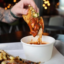 a taco being dipped into a sauce