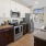 a kitchen with white cabinets brown cabinets a stovetop and a sink and a fridge