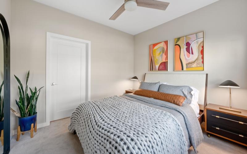 a bedroom with a bed and a fan and side table